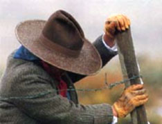 man wearing a hat while fixing a fence